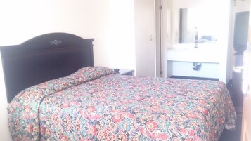 Una cama con una colcha de estampado floral y un cabecero oscuro en una habitación de hotel.