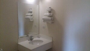 Une salle de bain avec un lavabo blanc, un miroir et un porte-serviettes avec des serviettes.
