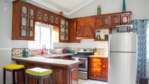 Een keuken met houten kastjes, een roestvrijstalen koelkast en een betegelde achterwand.