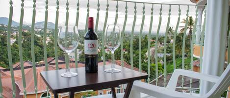 A balcony with a table, two wine glasses, and a bottle of wine.