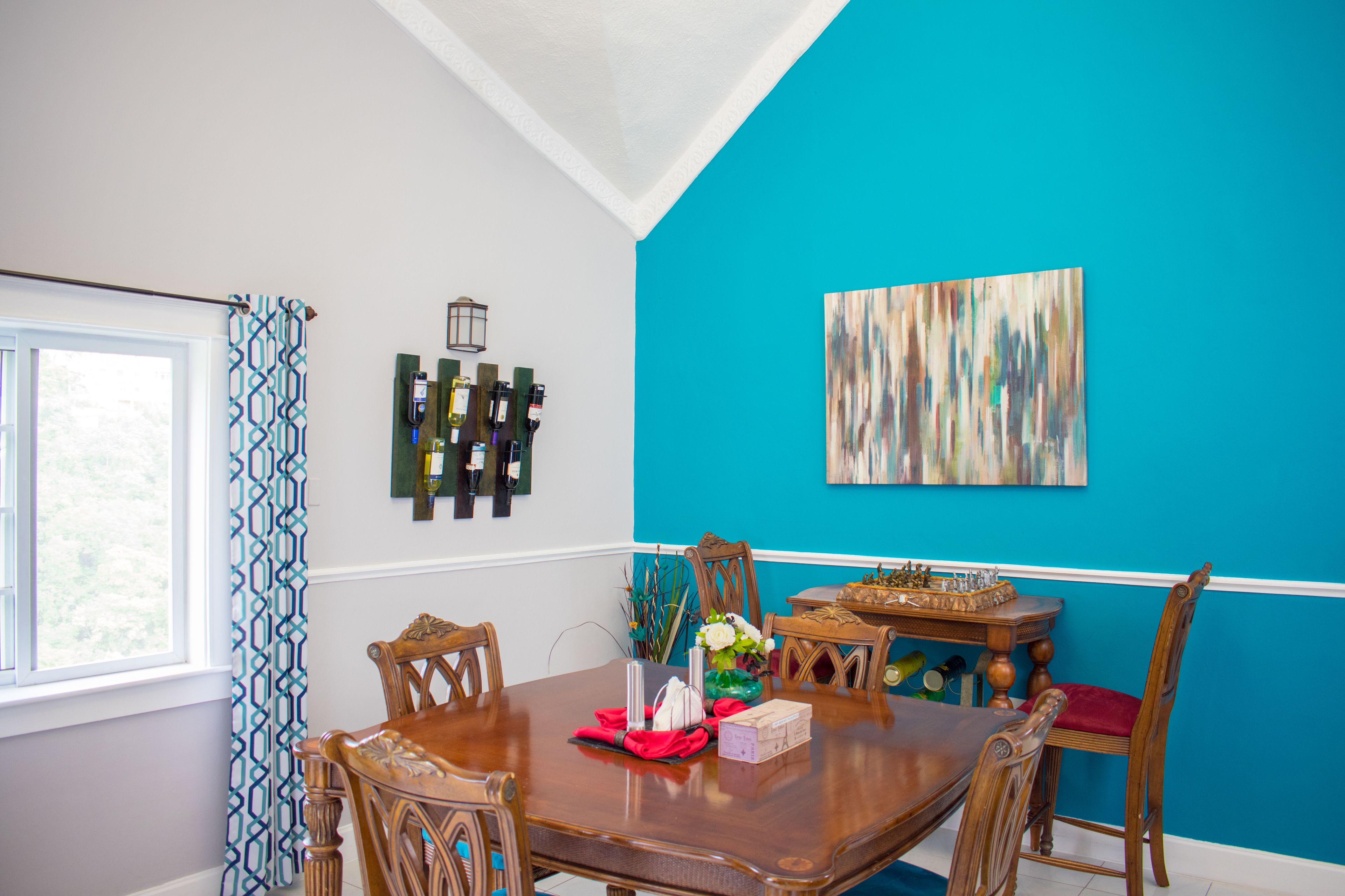 A dining room with a wooden table, chairs, and a blue accent wall.