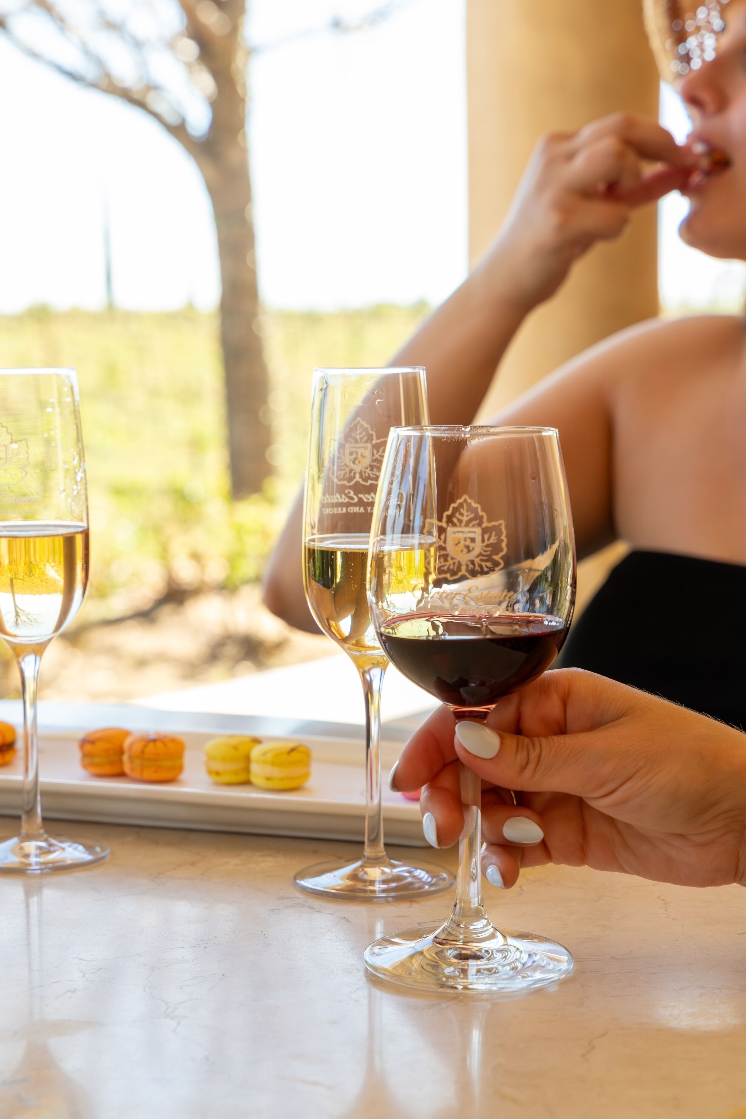 Un tavolo con bicchieri da vino e un vassoio di macarons.