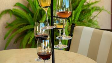 A hand holding a wine glass rack with four glasses on a round table.