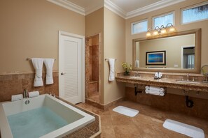 A bathroom with a bathtub, a shower, a vanity with a sink, and a large mirror.