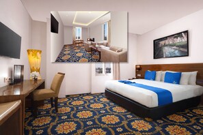 A hotel room with a large bed, a desk with a chair, a television, and a painting on the wall. - Hotel Namira Syariah Pekalongan (Pekalongan)
