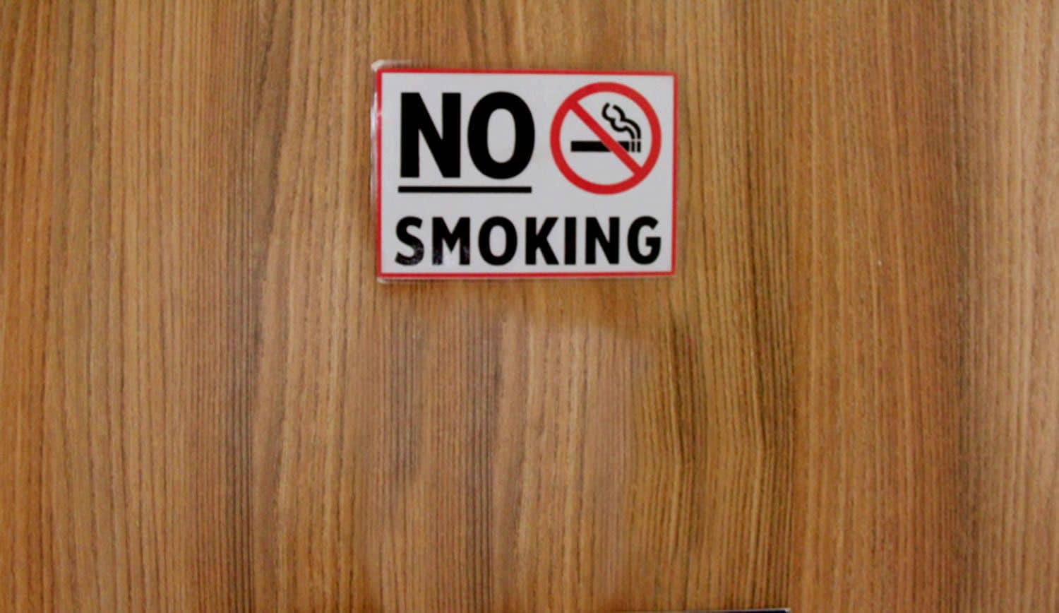 Un letrero de 'NO FUMAR' en una puerta de madera.
