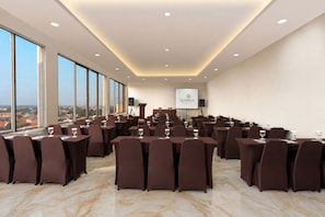 A conference room with a city view, equipped with tables and chairs, and a presentation screen. - Hotel Namira Syariah Pekalongan (Pekalongan)