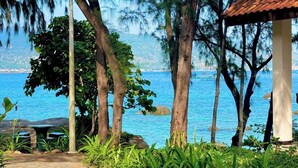 A stone pathway leading to a gazebo overlooking a coastal area with trees and a view of the sea.