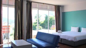 A hotel room with a bed, a sofa, a small table, and a view of the outdoors. - Kata Sea Boutique (Karon)