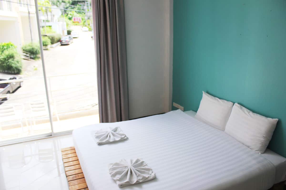 A hotel room with a large bed, two pillows, and two towels folded on the bed.