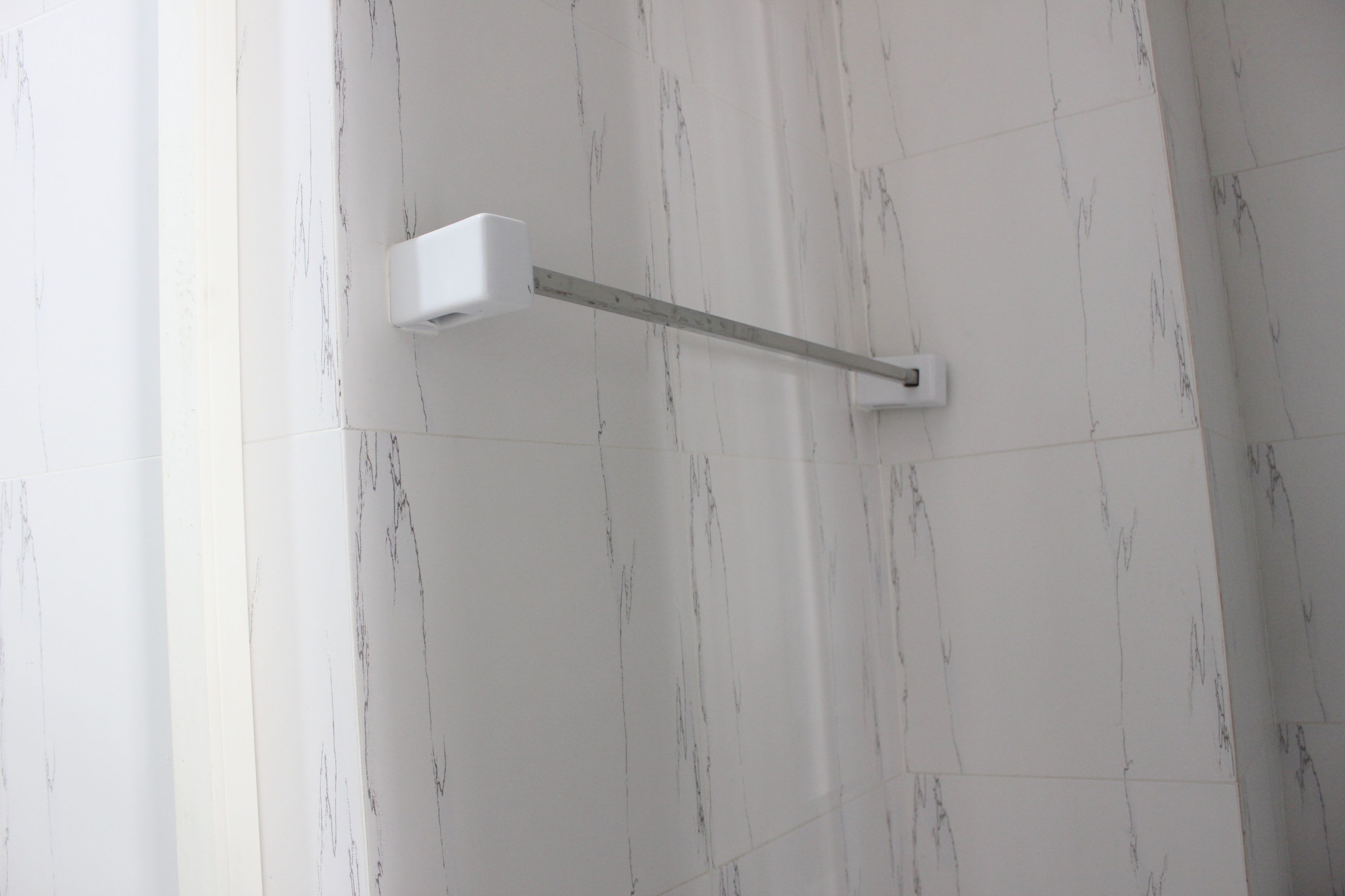 A bathroom with white marble tiles and a white towel rack.
