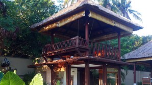 Una struttura tradizionale in legno con tetto di paglia, un balcone e un letto con coperta a righe.
