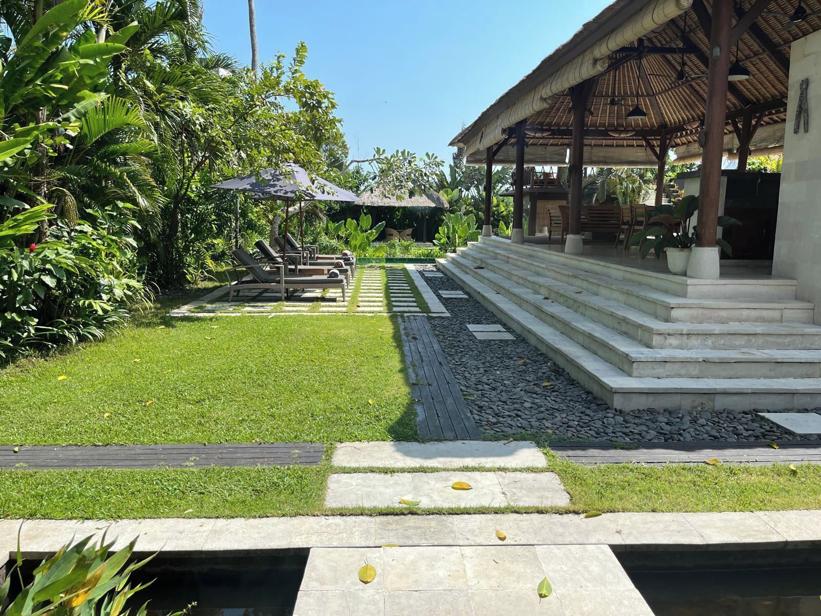 Ein gepflegter Garten mit Pool, Liegestühlen und einer überdachten Sitzgelegenheit.
