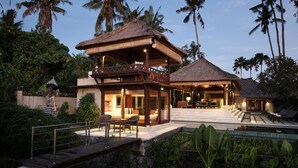 Un resort con piscina, una zona esterna coperta e un edificio a due piani con balcone.