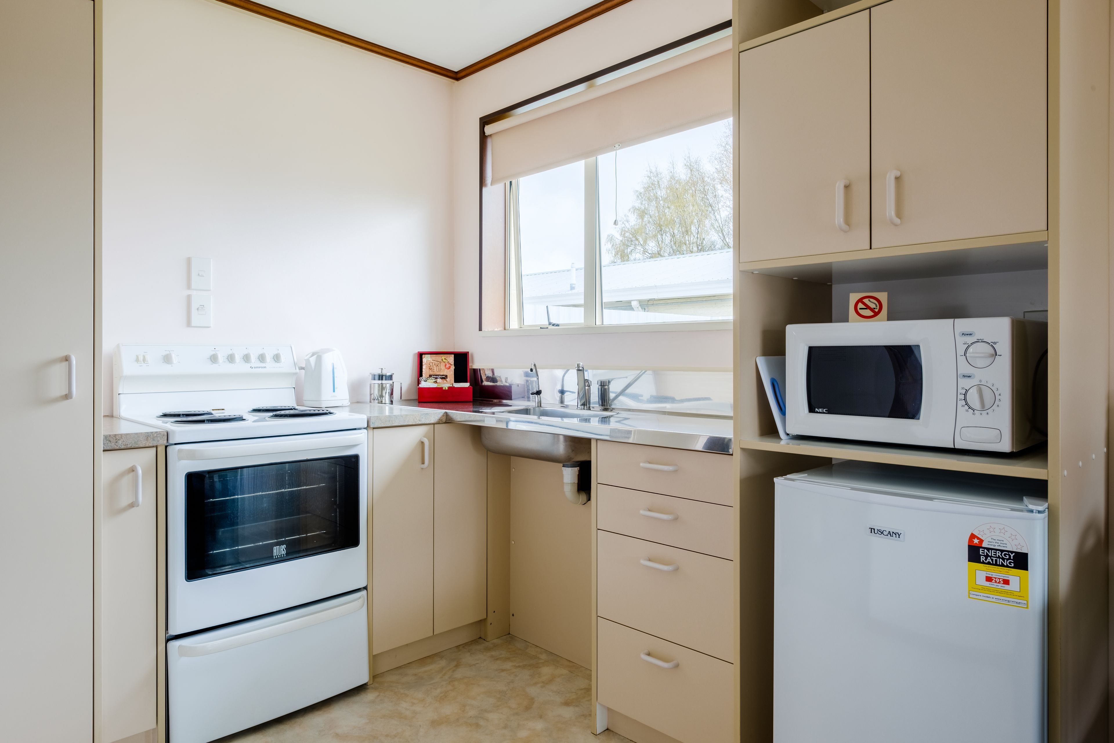 A compact kitchen with a built-in oven, a microwave, and a refrigerator.