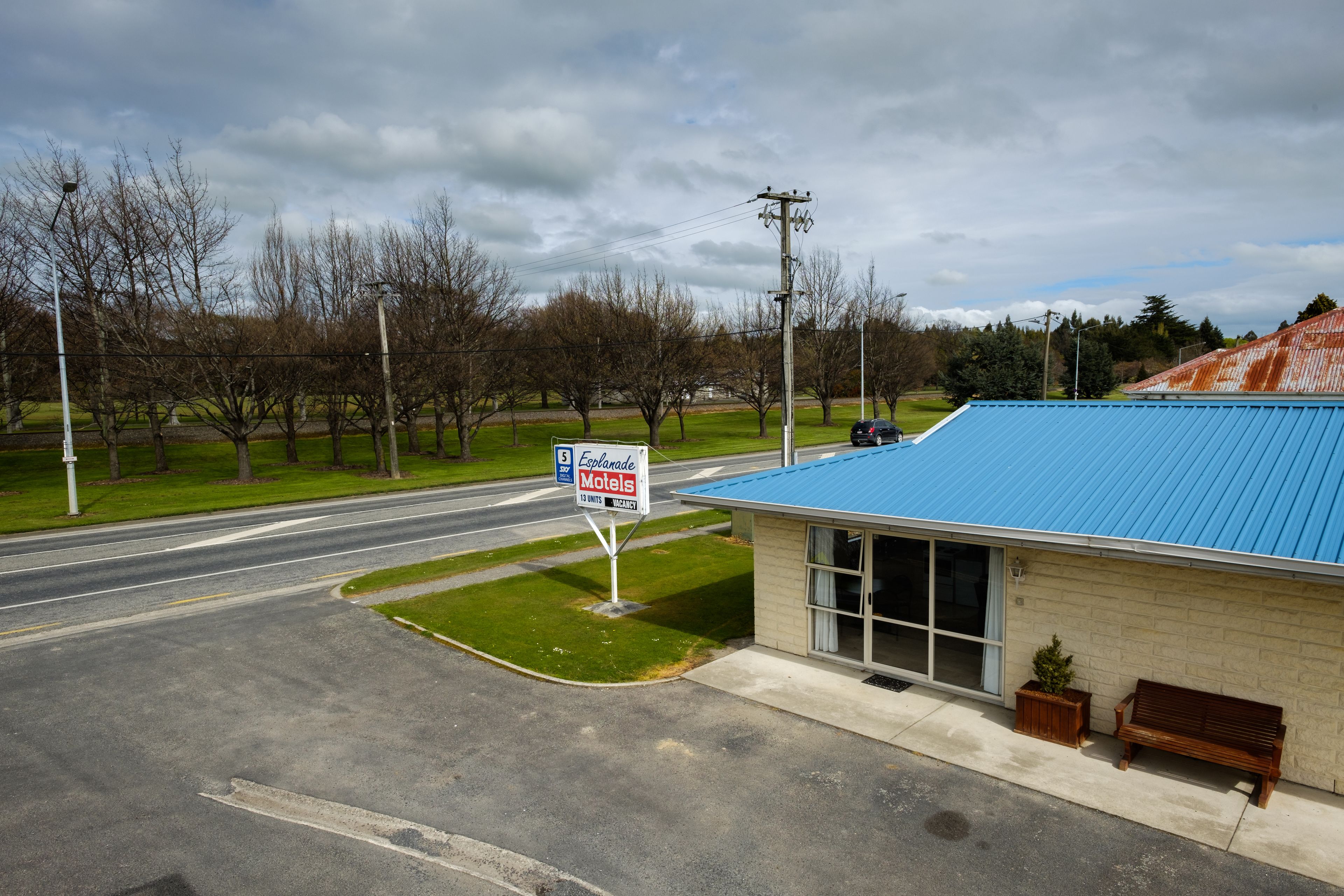 Un motel con techo azul, un letrero y una banca afuera.