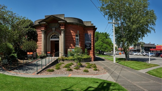 A brick building with a dome roof, a staircase leading to the entrance, and a sign indicating it is open.