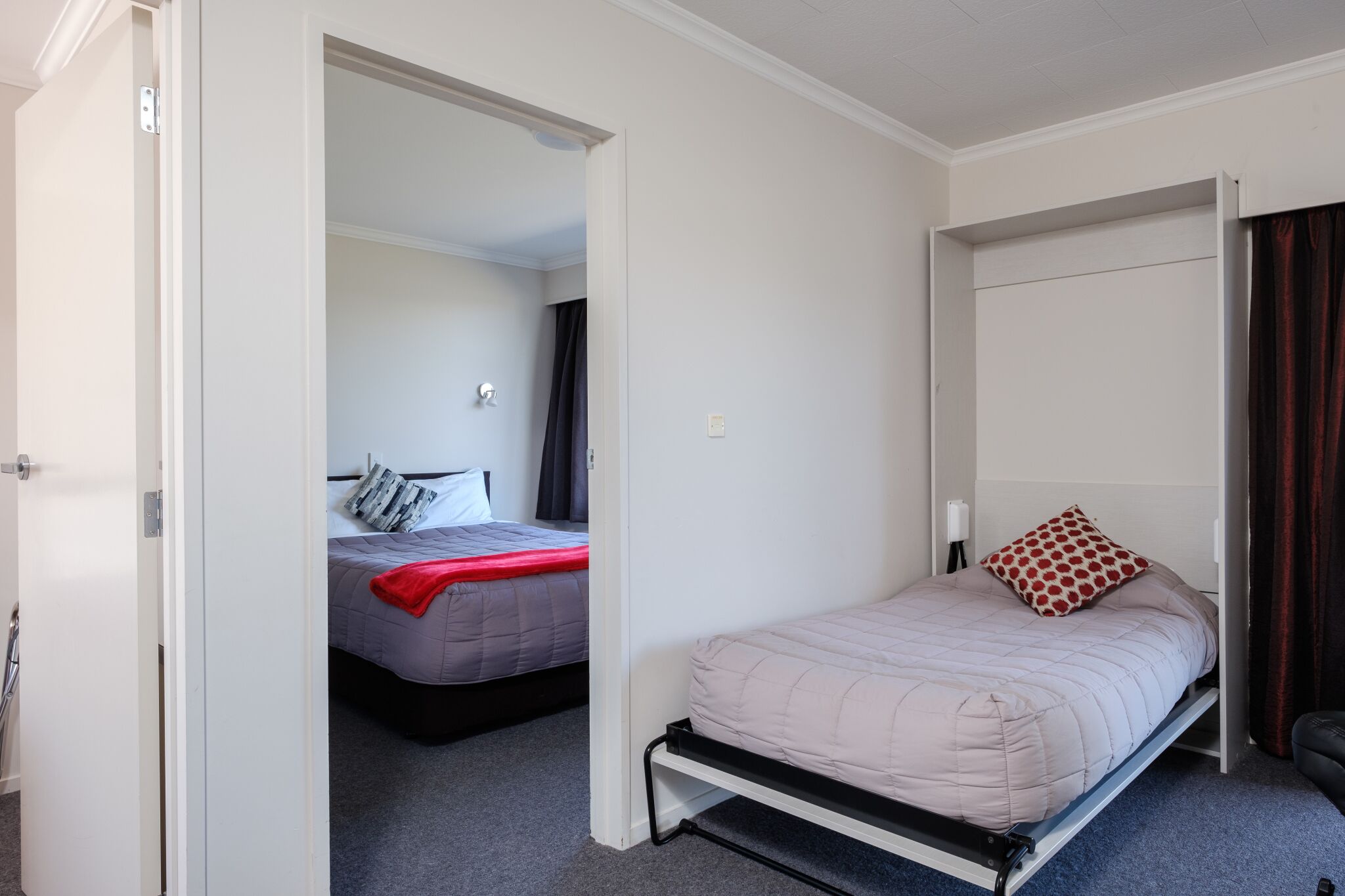 Ein Schlafzimmer mit einem Einzelbett, einem Kleiderschrank und einer Tür zu einem anderen Raum.