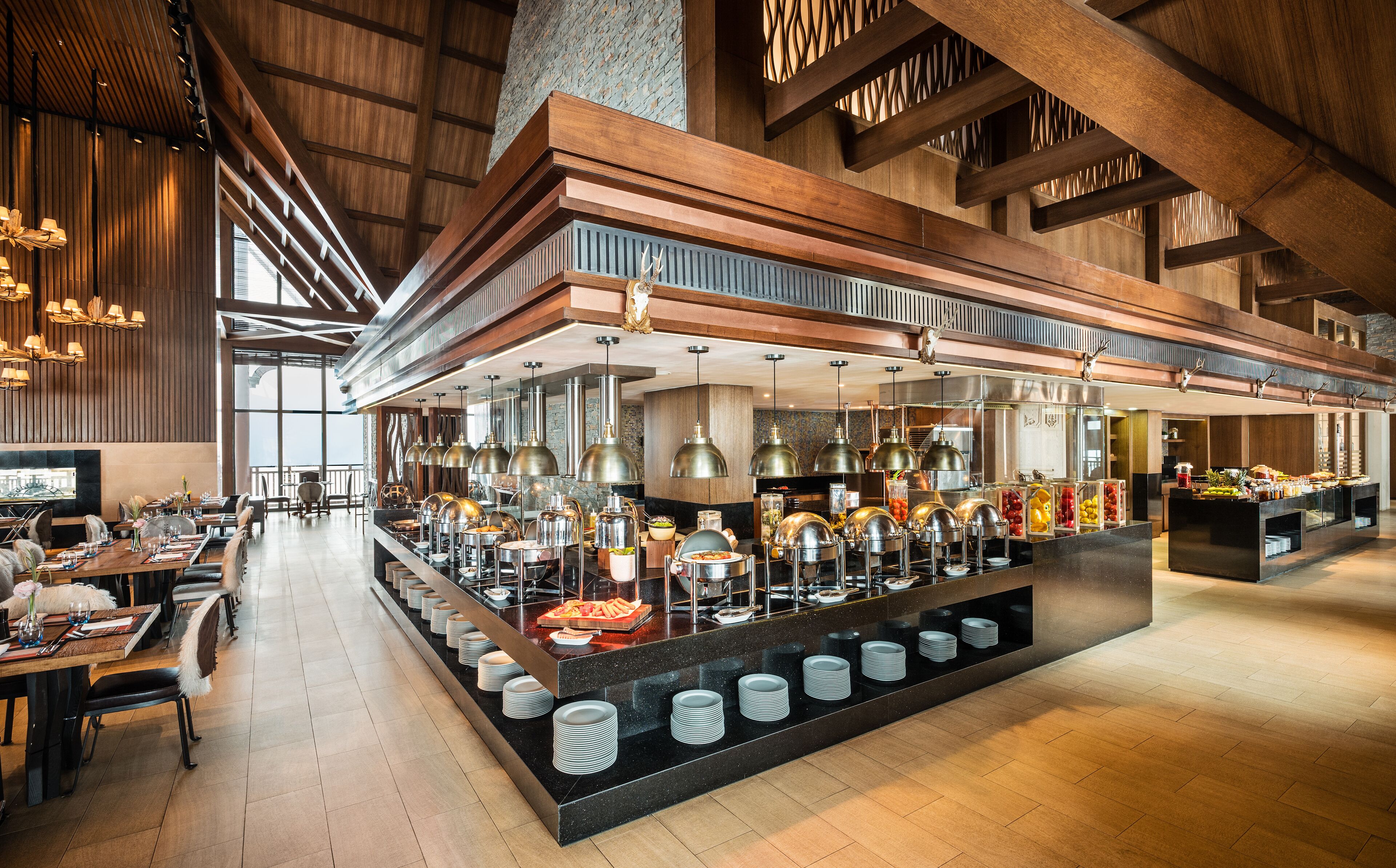 A spacious buffet area with multiple serving stations, a high ceiling with wooden beams, and a modern interior design.