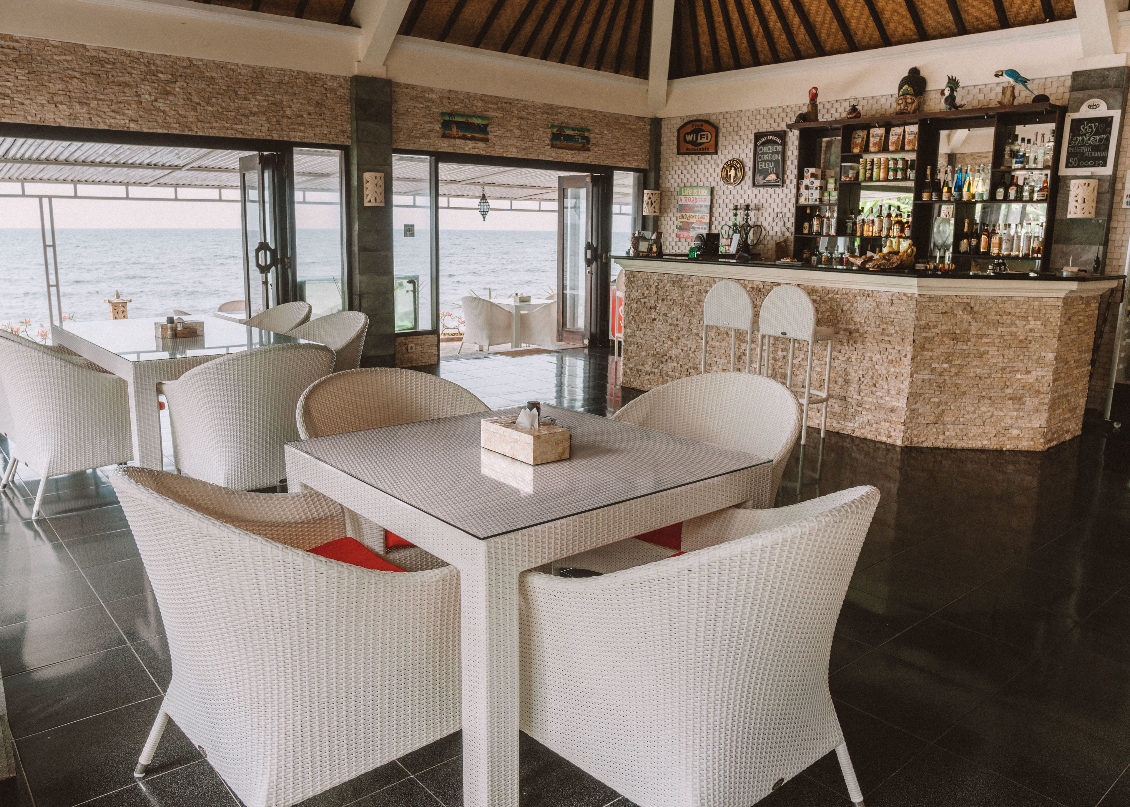 A bar area with wicker furniture and a view of the ocean.