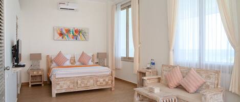 A bedroom with a bed, a sofa, a television, and a painting on the wall.