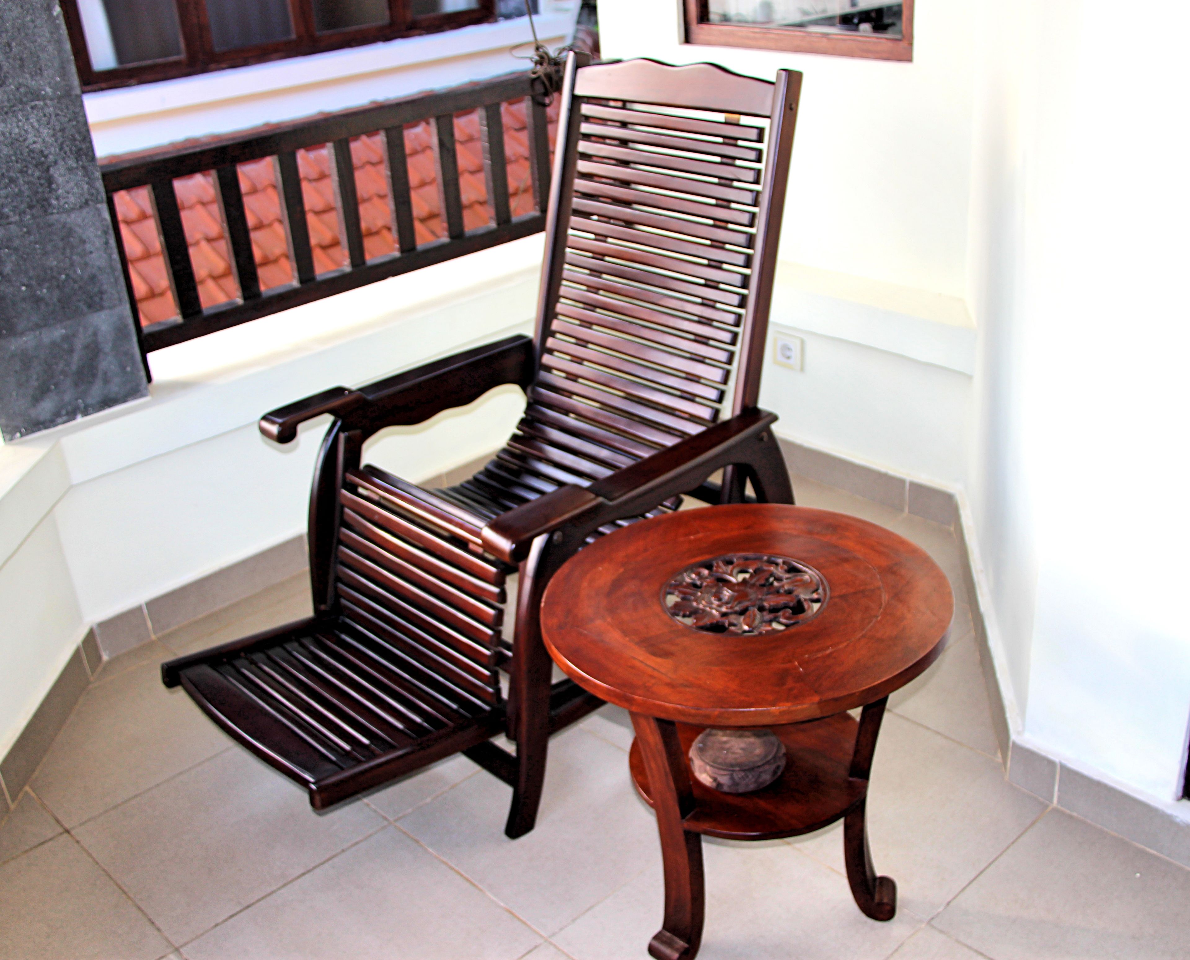 A wooden chair with a high backrest and a small round table with a decorative base.
