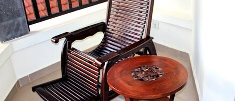 A wooden chair with a high backrest and a small round table with a decorative base.