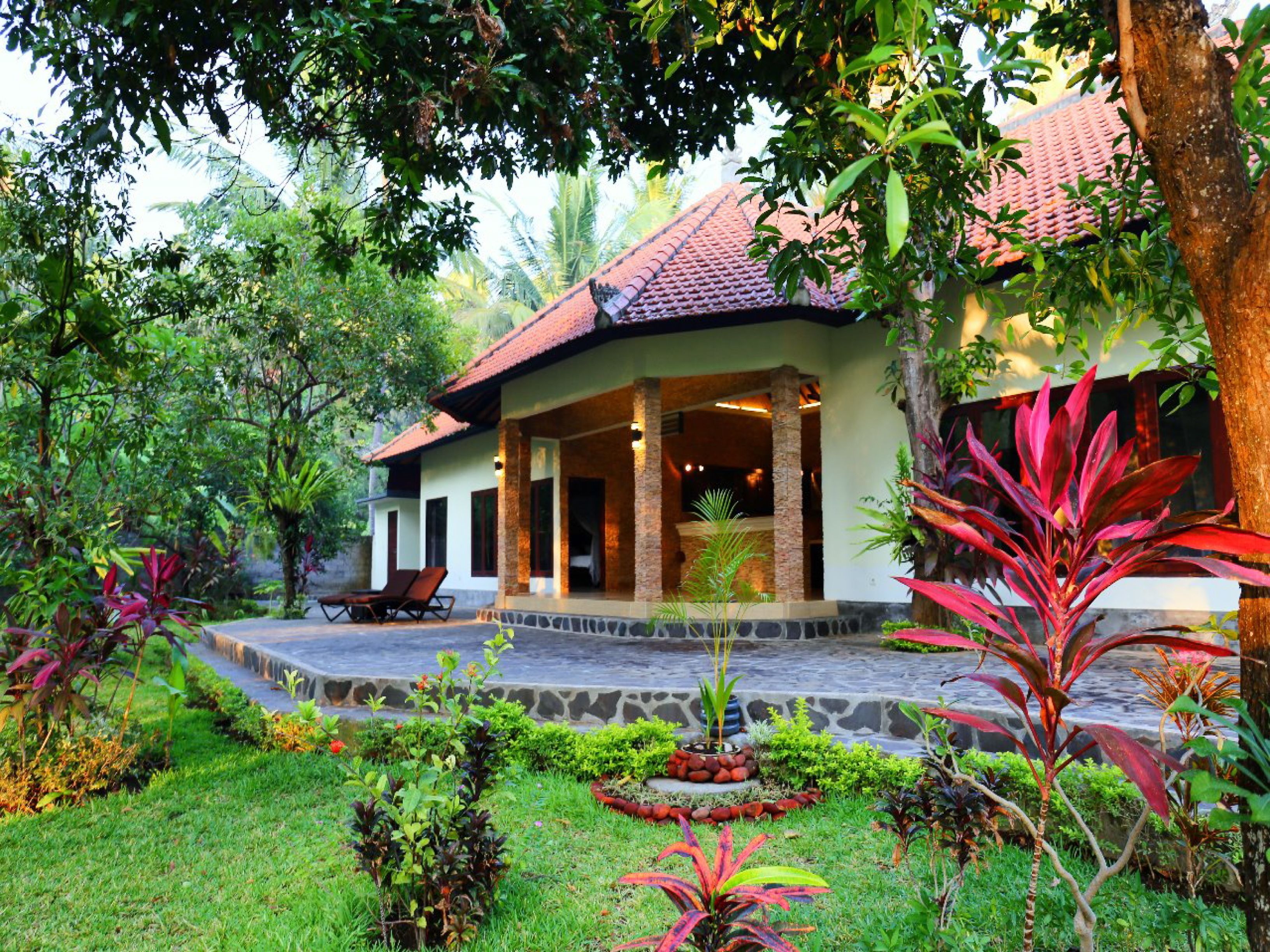 A house with a covered porch, stone steps, and a garden with various plants.