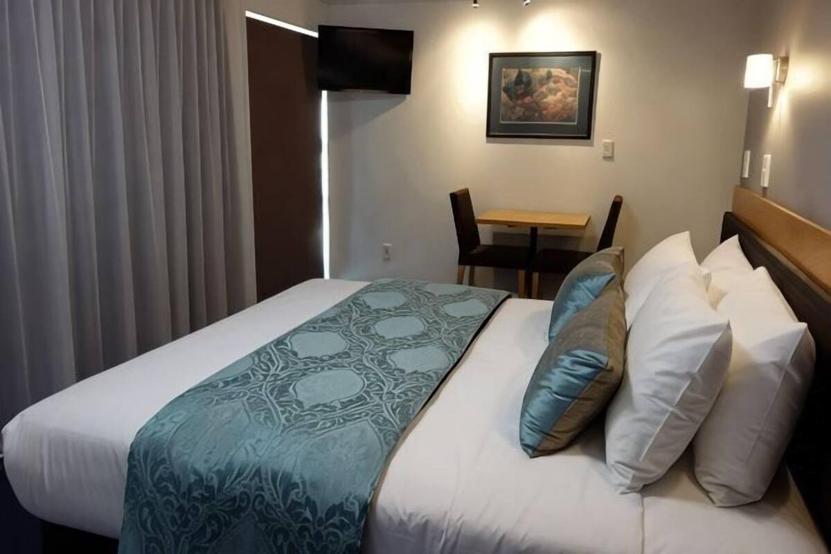 A hotel room with a bed, a desk, and a chair.