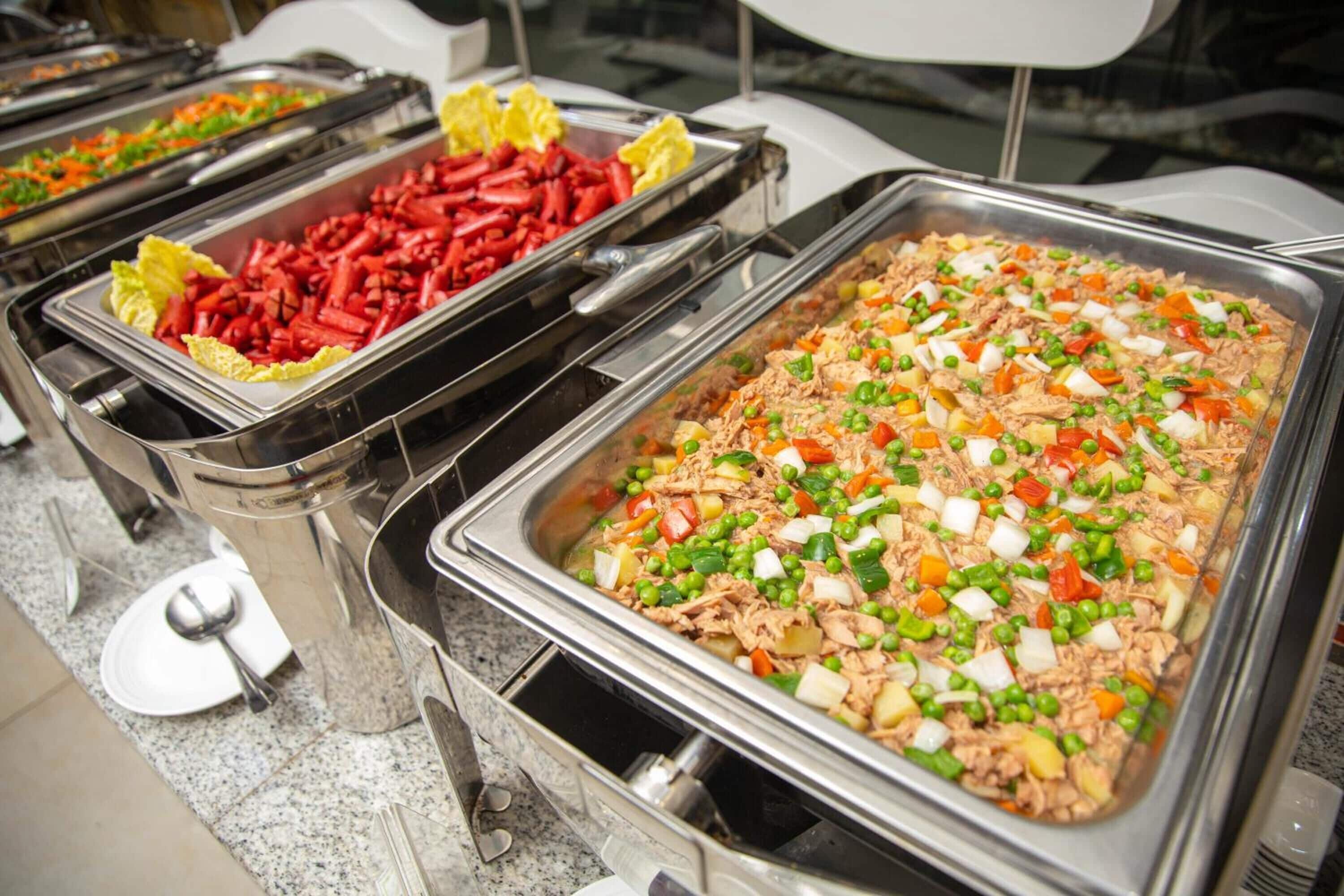 A buffet with various dishes including shredded meat, vegetables, and possibly some pasta.