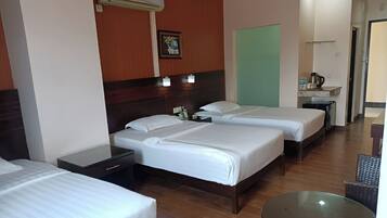 A hotel room with two beds, a small table, a nightstand, an air conditioning unit, and a green partition wall.