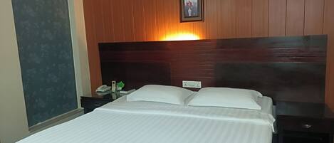 Habitación de hotel con una cama grande, una mesita de noche, un teléfono en la pared y un cuadro enmarcado sobre la cama.