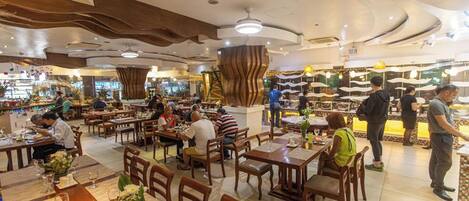 A spacious restaurant with multiple dining areas, wooden furniture, and a central decorative column.
