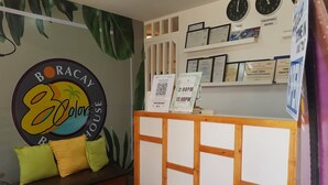 A reception area with a sign reading "BORACAY Ecolodge," a wooden reception desk, a seating area with cushions, and framed certificates on the wall. - 8Colors Beach House (Boracay Island)