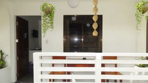 A hallway with a white railing, hanging plants, and a window with a reflection. - 8Colors Beach House (Boracay Island)