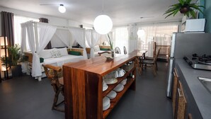 A modern, well-lit room with a dining table, chairs, a sofa with a canopy, and a kitchen area with a refrigerator and stove. - 8Colors Beach House (Boracay Island)