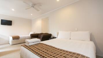 A hotel room with a large bed, a sofa, a TV, and a ceiling fan.