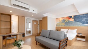 A modern hotel room with a sofa, a bed, a desk, and a dining area. - Metland Hotel Bekasi (Cikarang)