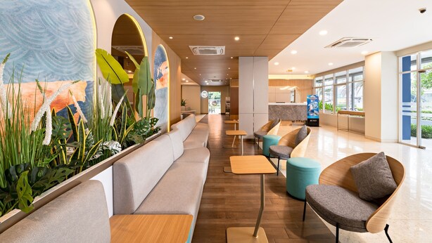 A modern lobby with a long reception desk, seating areas, and a large mural. - Metland Hotel Bekasi (Cikarang)