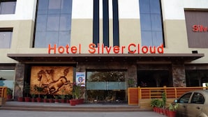 Hotel Silver Cloud con una entrada destacada, un mural de caballos y plantas en macetas.