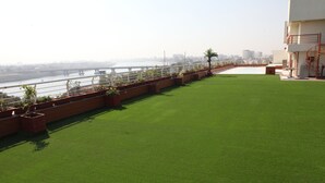 Una terraza en la azotea con césped artificial, vista a un río y un puente al fondo.