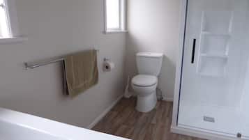 Een badkamer met toilet, een handdoekhouder en een douchehoek.