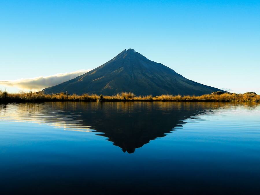 A mountain reflected in calm water with a clear sky.