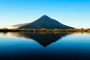 A mountain reflected in calm water with a clear sky.