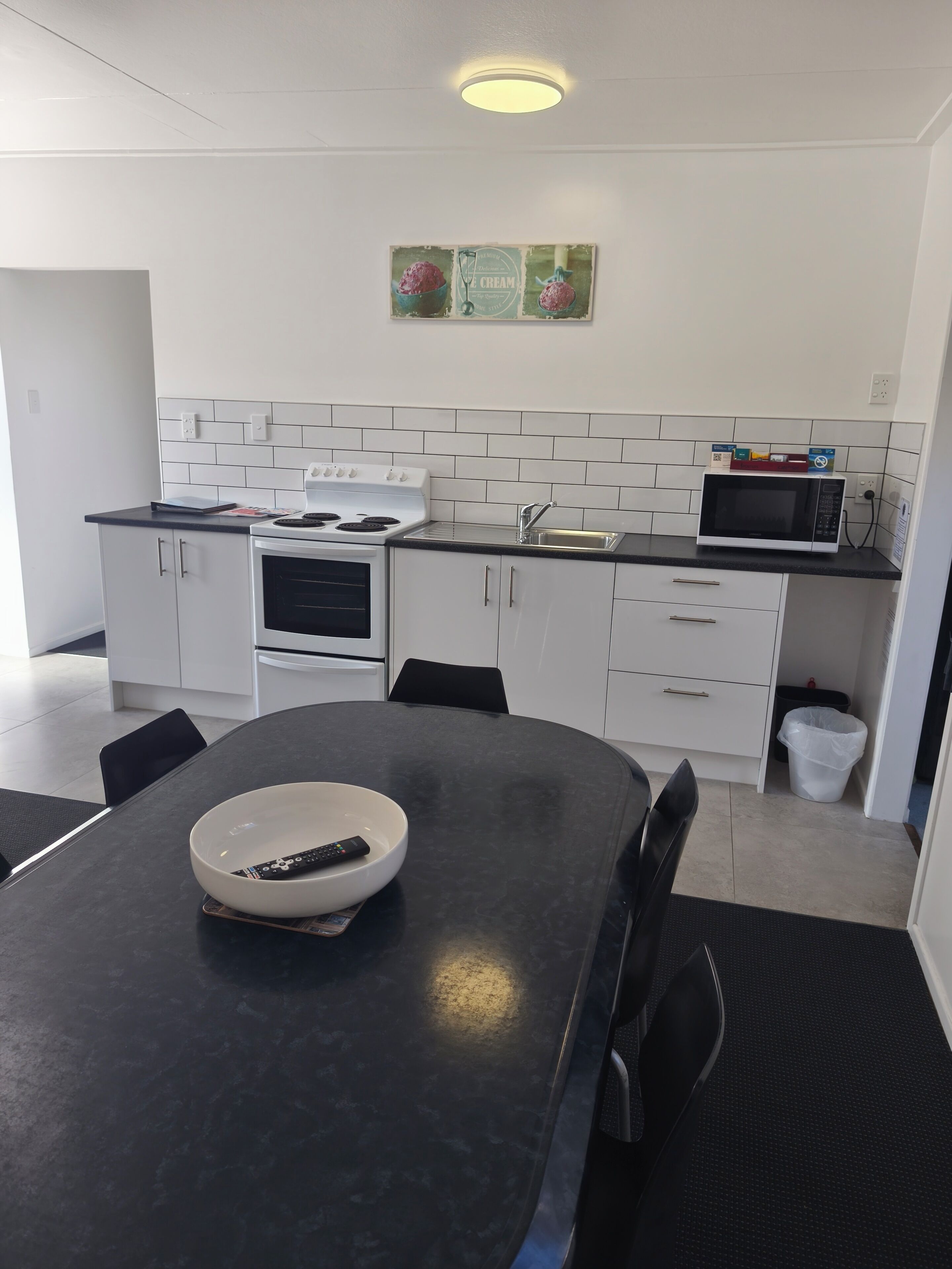 Une cuisine moderne avec des meubles blancs, un plan de travail noir, un four à micro-ondes et une cuisinière.