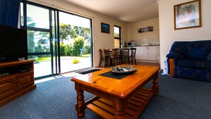 A living room with a wooden dining table, a television, and a sofa. - New Plymouth Top 10 Holiday Park (New Plymouth)