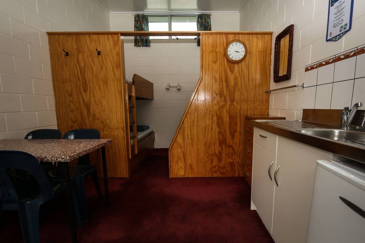 A compact kitchen with a wooden cabinet, a clock, and a sink.