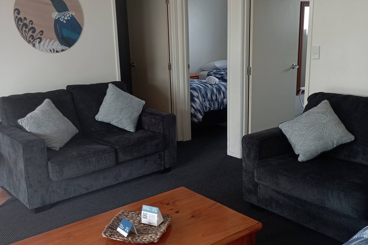 A room with two dark grey sofas, a wooden coffee table, and a patterned rug.
