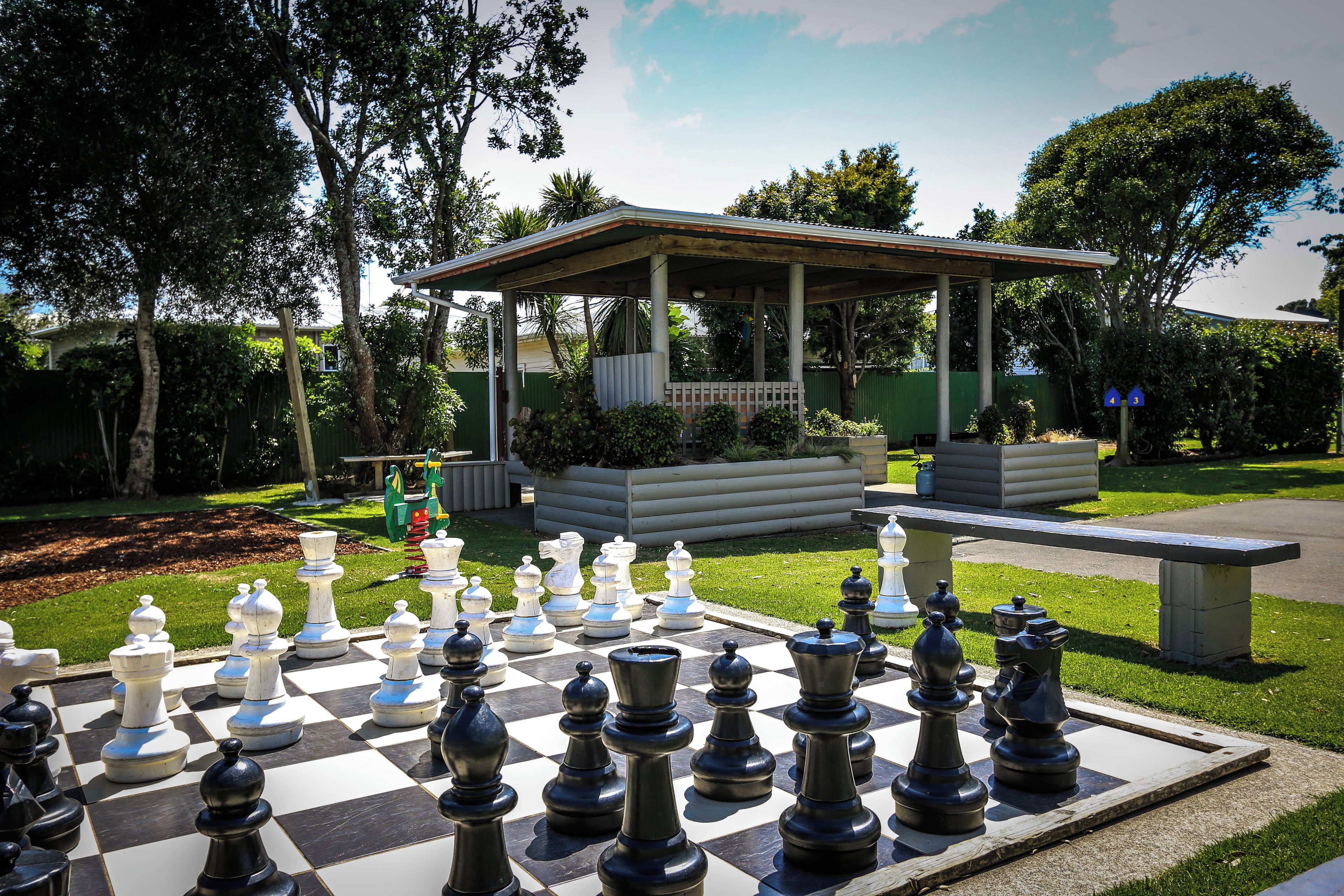 A chessboard set outdoors with a gazebo in the background.