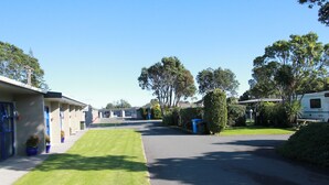 A row of single-story mobile homes with a paved driveway and well-maintained lawns. - New Plymouth Top 10 Holiday Park (New Plymouth)
